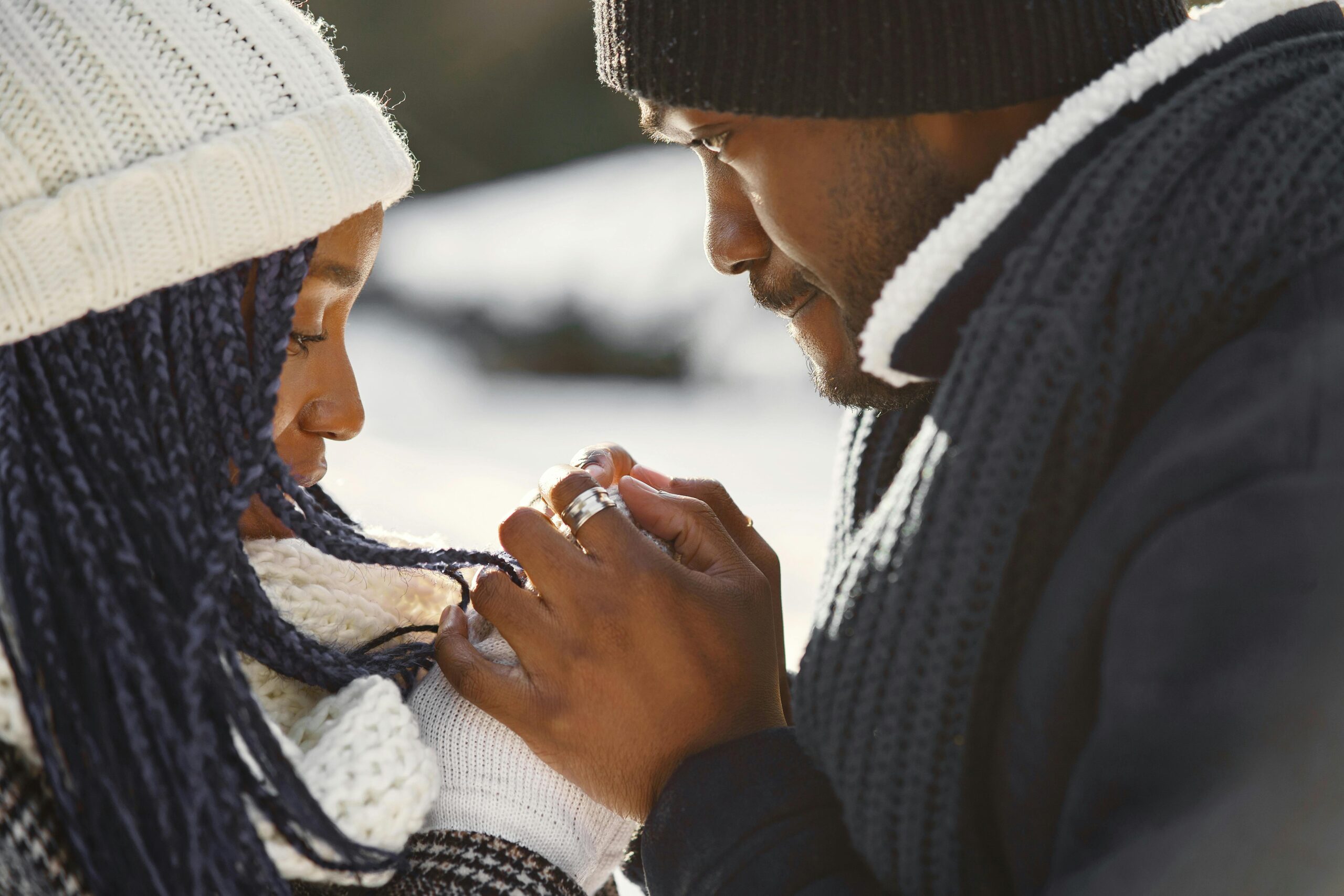 Close-up of a couple holding hands warmly dressed in winter attire outdoors.